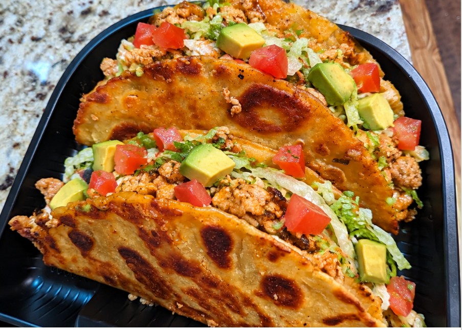 Seasoned chicken tacos with lettuce, tomato, sour cream and cheese